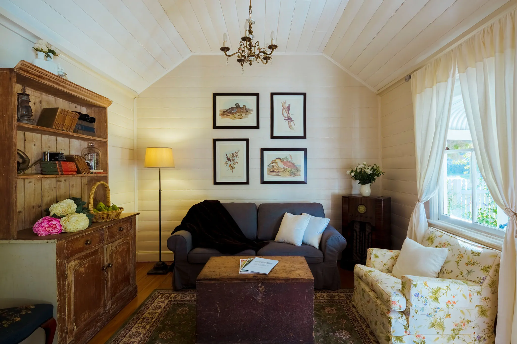 Sun-filled sitting room with sofas and framed bird prints